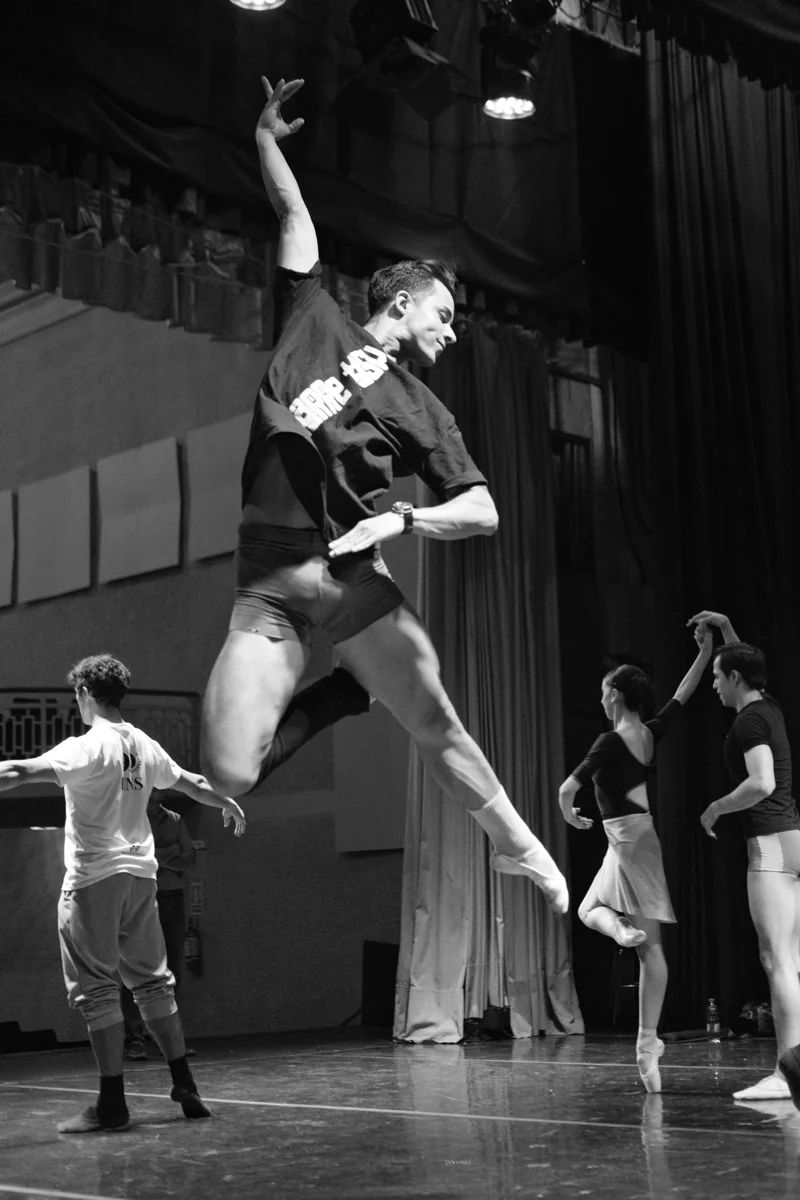 A black-and-white photograph of Lucas suspended in a jump in the studio